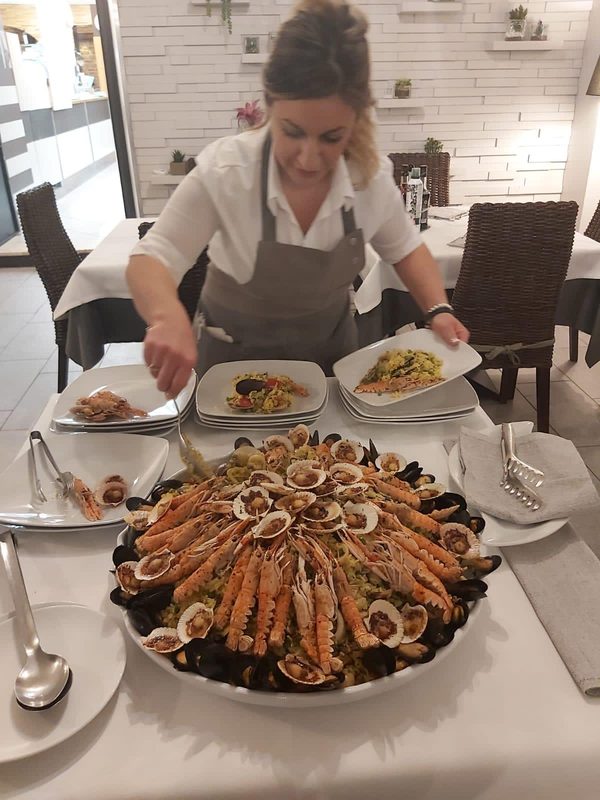 Cameriera che serve un grande piatto di crudi di mare in sala