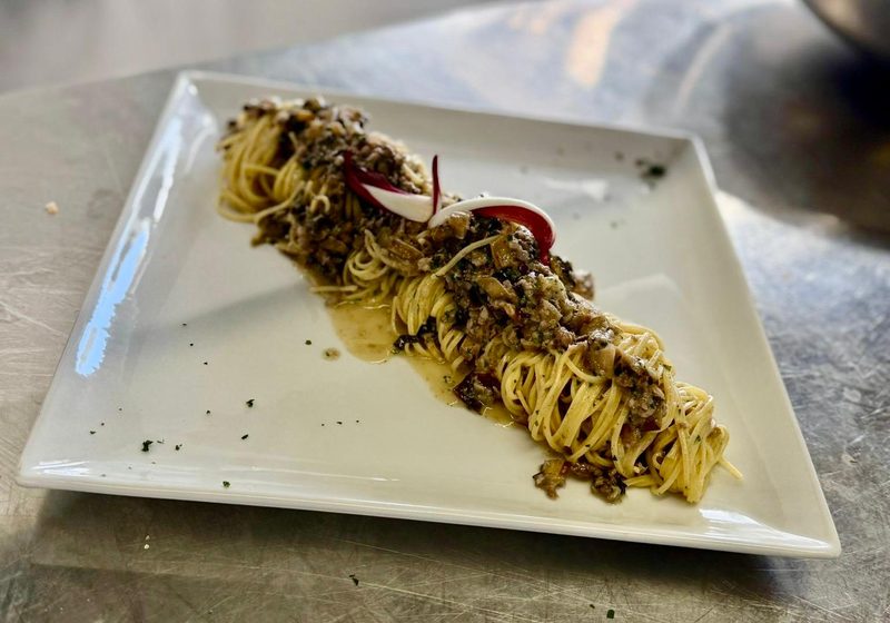 Tagliolini saltati serviti su piatto quadrato