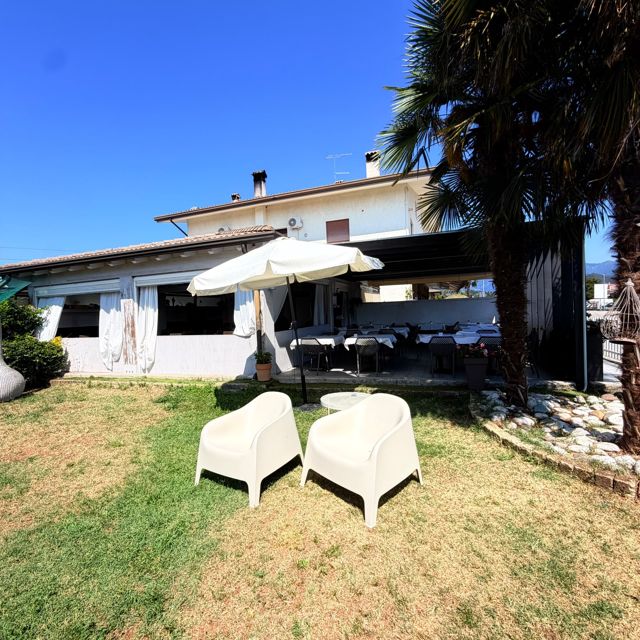 Esterno del locale con giardino, lettini e ombrellone