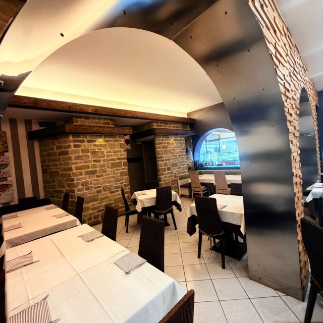 Sala con arco in mattoni a vista e tavoli apparecchiati